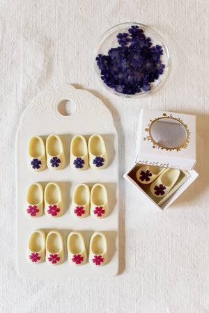Babyschuhe aus weißer Schokolade mit violetter Blüte